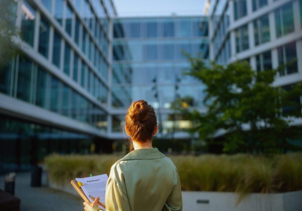 Woman holding clipboard outside modern building.
